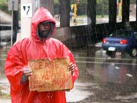 Man with sign in rain on interstate entrance